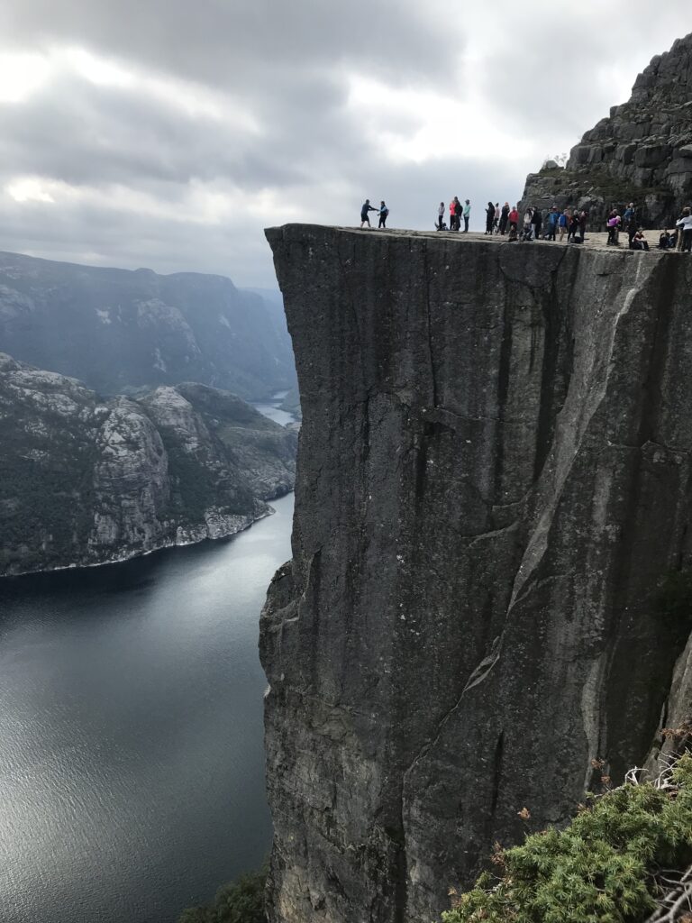 Tourists posing at Preikestolen (Pulpit Rock) rock formation in Forsand, Norway. The hiking trail up to the plateau has had to be closed a few times due to overcrowding that can create dangerous situations. (September 2018; Photo by Johan Edelheim)