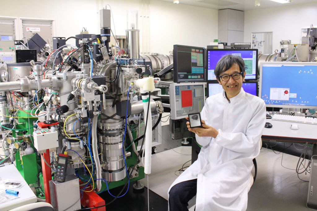 Dr. Yurimoto holding a meteorite in front of the isotope microscope.