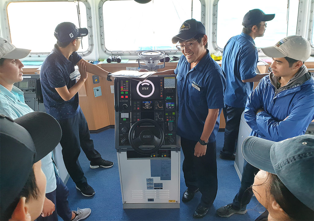 A crew member showing how to steer the ship.