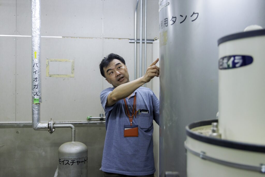 Director Ishii pointing to a biogas tank.