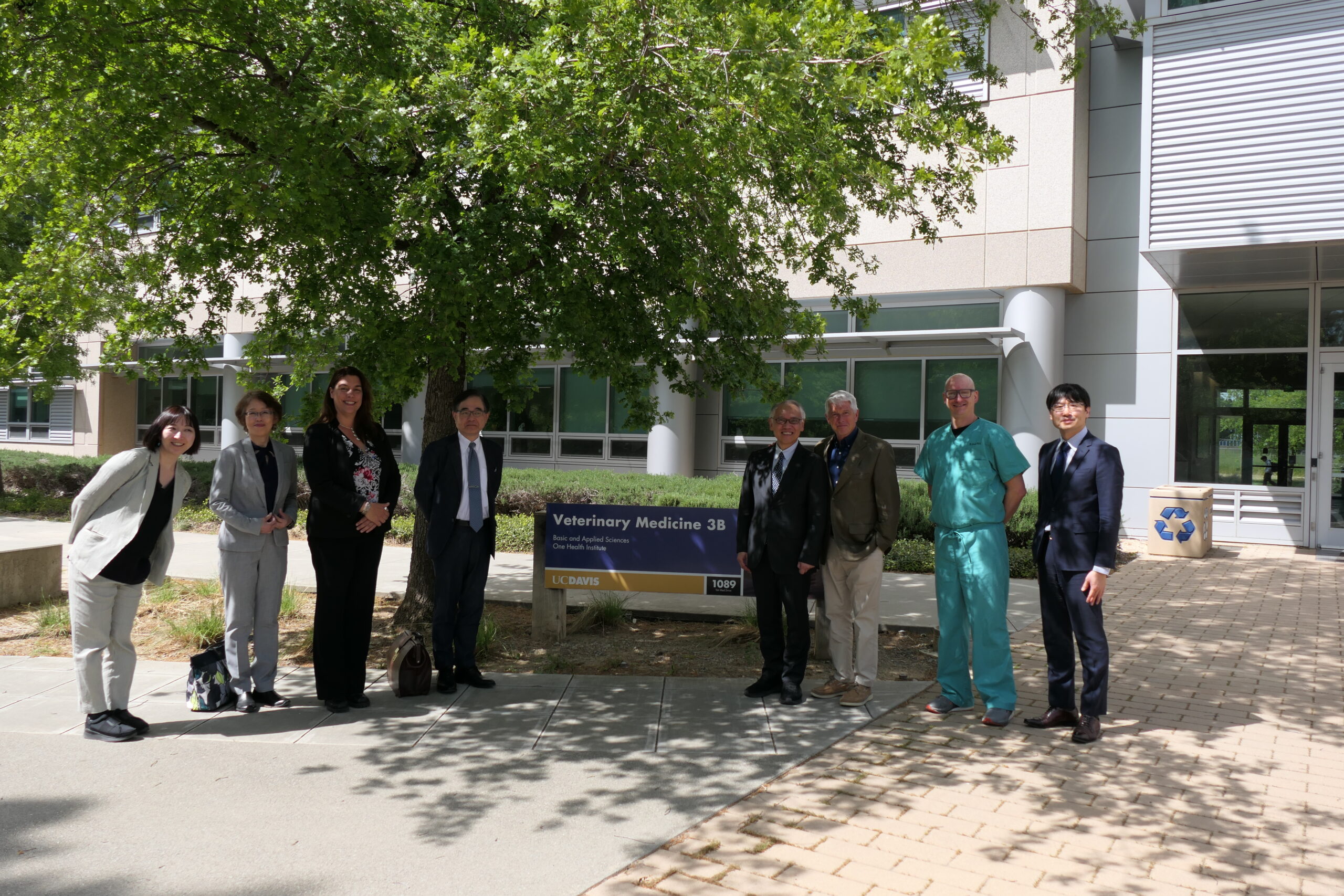 Eight people are standing in front of the Veterinary Medicine school sign.